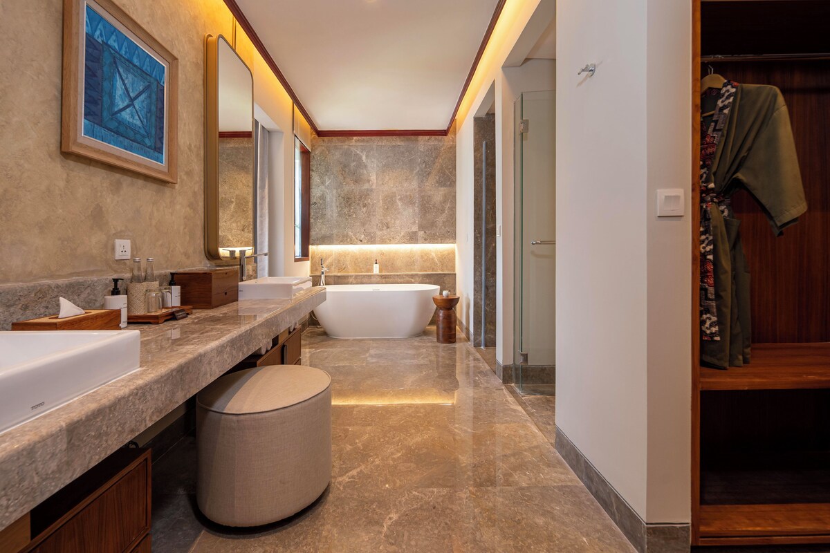 A modern bathroom with a bathtub, two sinks, a vanity, and a robe rack.