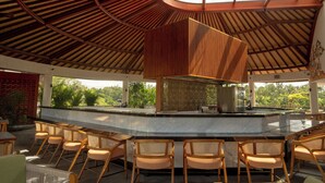Un bar moderno con techo curvo, sillas de madera y vistas a un exuberante paisaje exterior.