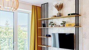 Un salon moderne doté d’un grand téléviseur, d’étagères en bois et offrant une vue sur la verdure grâce à une grande fenêtre.