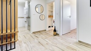 Un couloir doté d’un plancher en bois, une bouteille de vin et deux miroirs muraux.