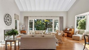 A spacious living room with a large sofa, a piano, and a dining area.