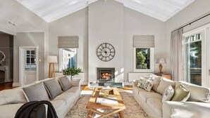 A spacious living room with a high ceiling, a fireplace, and two sofas facing each other.