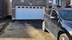Ein zweistöckiges Haus mit Garage, Auffahrt und einem geparkten SUV.