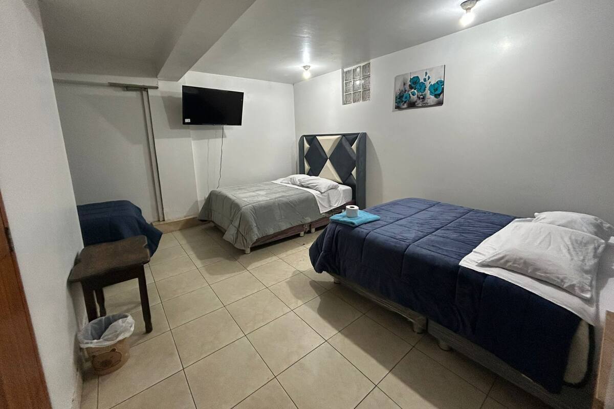 Ein Schlafzimmer mit zwei Betten, einem Fernseher und einem kleinen Tisch.