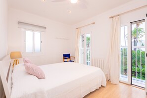 Een slaapkamer met een groot bed, een stoel, een raam en uitzicht op groen buiten.