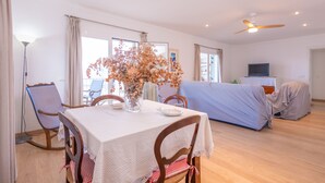 A dining area with a table set for two, a vase with dried flowers, and a ceiling fan. - TUGORES SIMÓ 2º A - Charming apartment on the beachfront in Can Picafort – Free Wi-Fi (Muro)