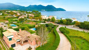 A coastal residential area with houses, a swimming pool, and a road leading to the sea. - FINCA ES FASSER - Charming country house with a private pool near the sea – Free Wi-Fi (Son Servera)