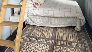 A bedroom with a bunk bed, a wooden ladder, a patterned rug, and a window. - Entire home in Auckland, New Zealand (Auckland)