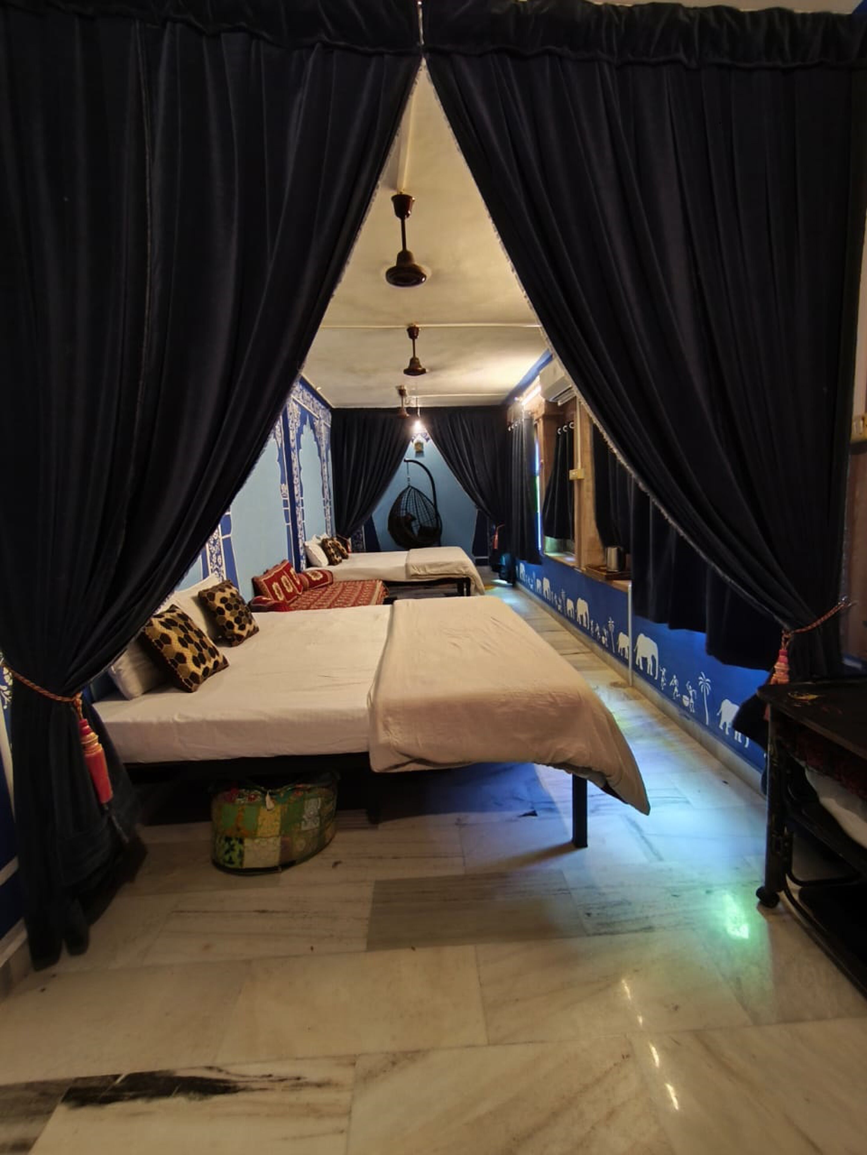 A room with a bed, a hanging chair, and a small table.
