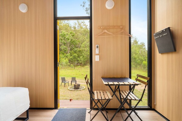 Una habitación moderna con detalles de madera, una cama, una mesa con sillas y vistas al exterior.