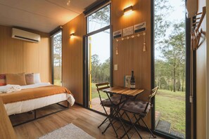 Une chambre moderne avec un lit, une table et des chaises, une fenêtre et une vue sur l’extérieur.
