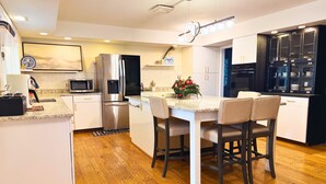 Una cocina moderna con una isla central, electrodomésticos de acero inoxidable y una zona de comedor con taburetes de bar.