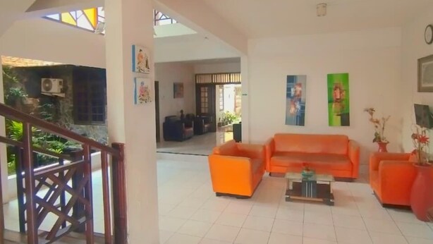 A spacious living area with a high ceiling, a staircase, and a view of a garden. - Hommy Inn Timoho (Yogyakarta)
