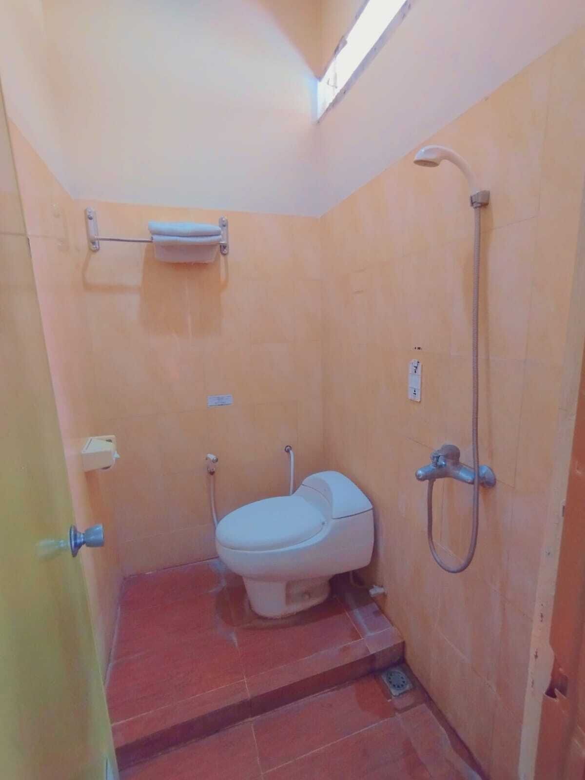 A small, compact bathroom with a toilet, a shower, and a towel rack.