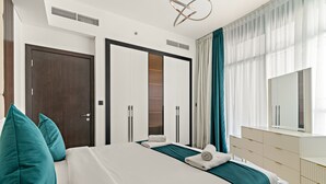Hotellihuone, jossa on suuri sänky, kaksi yöpöytää, vaatekaappi ja peili.