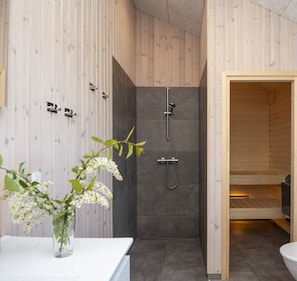 Une salle de bain moderne Ă©quipĂ©e dâune douche, de toilettes et dâun lavabo agrĂ©mentĂ© dâun vase de fleurs.