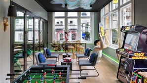 Ein Zimmer mit Tischfußball, einem Space Invaders-Automaten und Blick auf die Gebäude draußen.