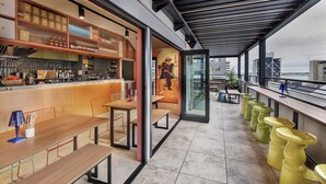 Eine moderne Bar mit einer langen Theke, Sitzgelegenheiten und einem Wandgemälde.