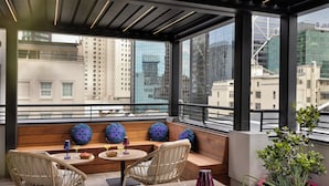Ein zeitgenössischer Stadtbalkon mit Korbstühlen, einem kleinen runden Tisch und einem Blumentopf.