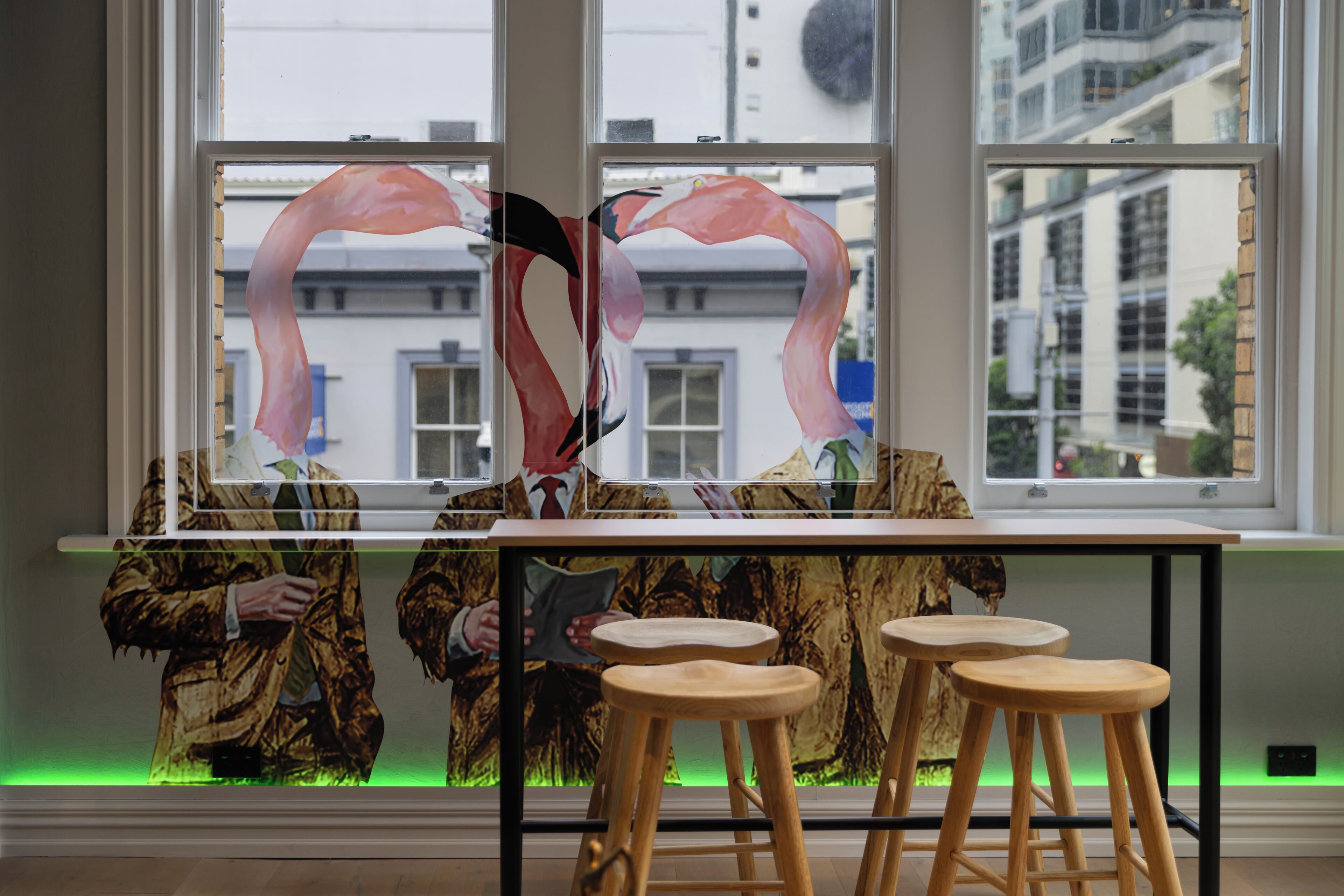 Une pièce dotée d’une grande fenêtre, d’une table avec des tabourets et d’une fresque murale.
