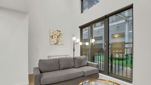 Un salon moderne avec un canapé gris, une table basse en verre et un lampadaire.