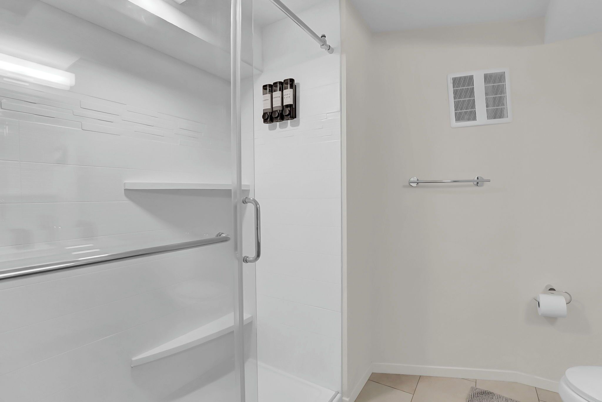 A modern bathroom with a glass shower enclosure, a toilet, and a towel rack.