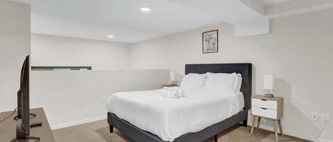 Une chambre à coucher avec un lit, une table de chevet, une lampe et un téléviseur posé sur un bureau.