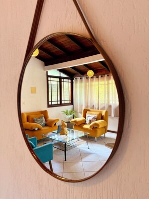 Ein Wohnzimmer mit zwei gelben Sofas, einem Glastisch und einem blauen Sessel.