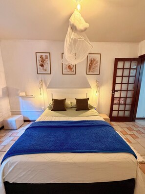 Ein Schlafzimmer mit einem Bett, Nachttischlampen, einem Nachttisch, einer Tür und gerahmten Wandbildern.