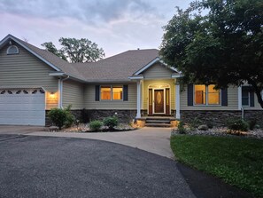 A two-story house with a garage, a front porch, and a stone foundation.