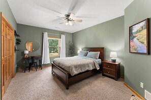 A bedroom with a bed, a desk, a chair, a ceiling fan, and a window with curtains. - The River House - 4 BR Retreat on the Apple River (Star Prairie)