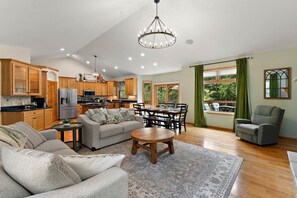 A spacious living room with a sofa, coffee table, and dining area. - The River House - 4 BR Retreat on the Apple River (Star Prairie)