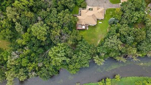 A house surrounded by dense greenery and a river.
