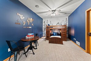 A child's bedroom with a bunk bed, a desk with a chair, a world map on the wall, and a ceiling fan. - The River House - 4 BR Retreat on the Apple River (Star Prairie)