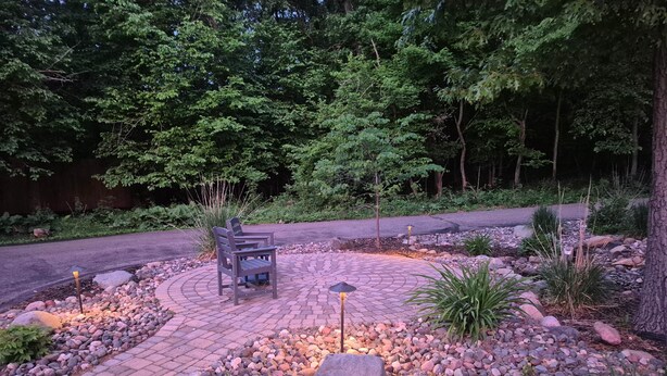 A paved outdoor area with a bench, rocks, and plants.