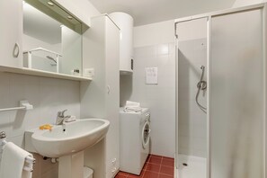 A bathroom with a sink, mirror, washing machine, and shower. - Appartamento Tracce Di Neve (Sestriere)