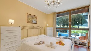 A hotel room with a bed, a dresser, a window with a view of the street, and a chandelier. - Appartamento Tracce Di Neve With Parking for 4 (Sestriere)