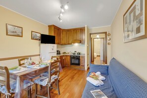 Un espacio habitable compacto con comedor, kitchenette y sofá.