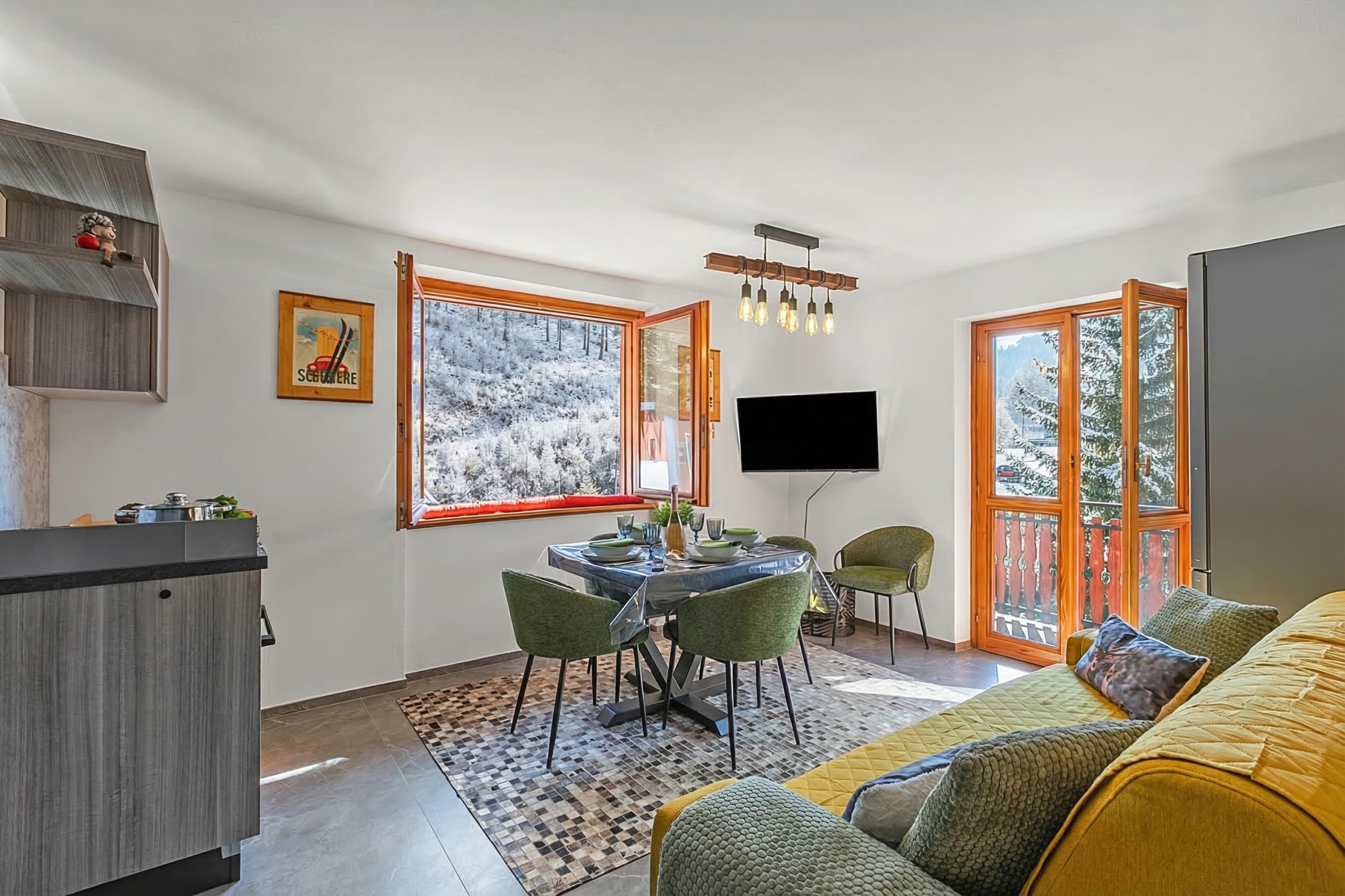 A modern living space with a dining area, a sofa, and a TV mounted on the wall.