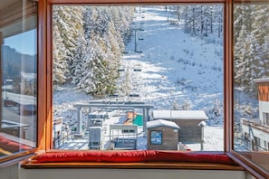 Een uitzicht op een besneeuwde piste met een skilift en gebouwen op de achtergrond.