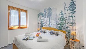 A neatly made bed with white linens, a window with curtains, a wall mural of trees, and a bedside lamp. - Appartamento Nube Di Argento Near Ski Lift (Sestriere)
