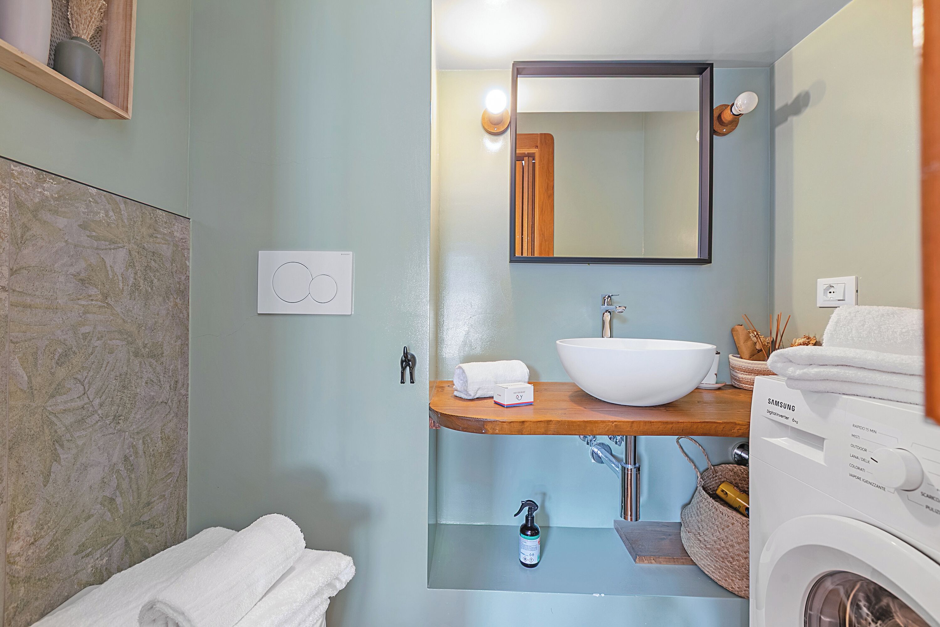 A bathroom with a white sink, a mirror, a towel rack, and a washing machine.