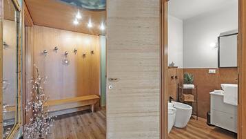 A bathroom with a wooden bench, a sink, and a toilet.
