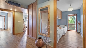 A spacious room with a large bed, a wooden floor, a mirror, and a view of the outdoors. - Appartamento Alpine Suite Ski-in/out (Sestriere)