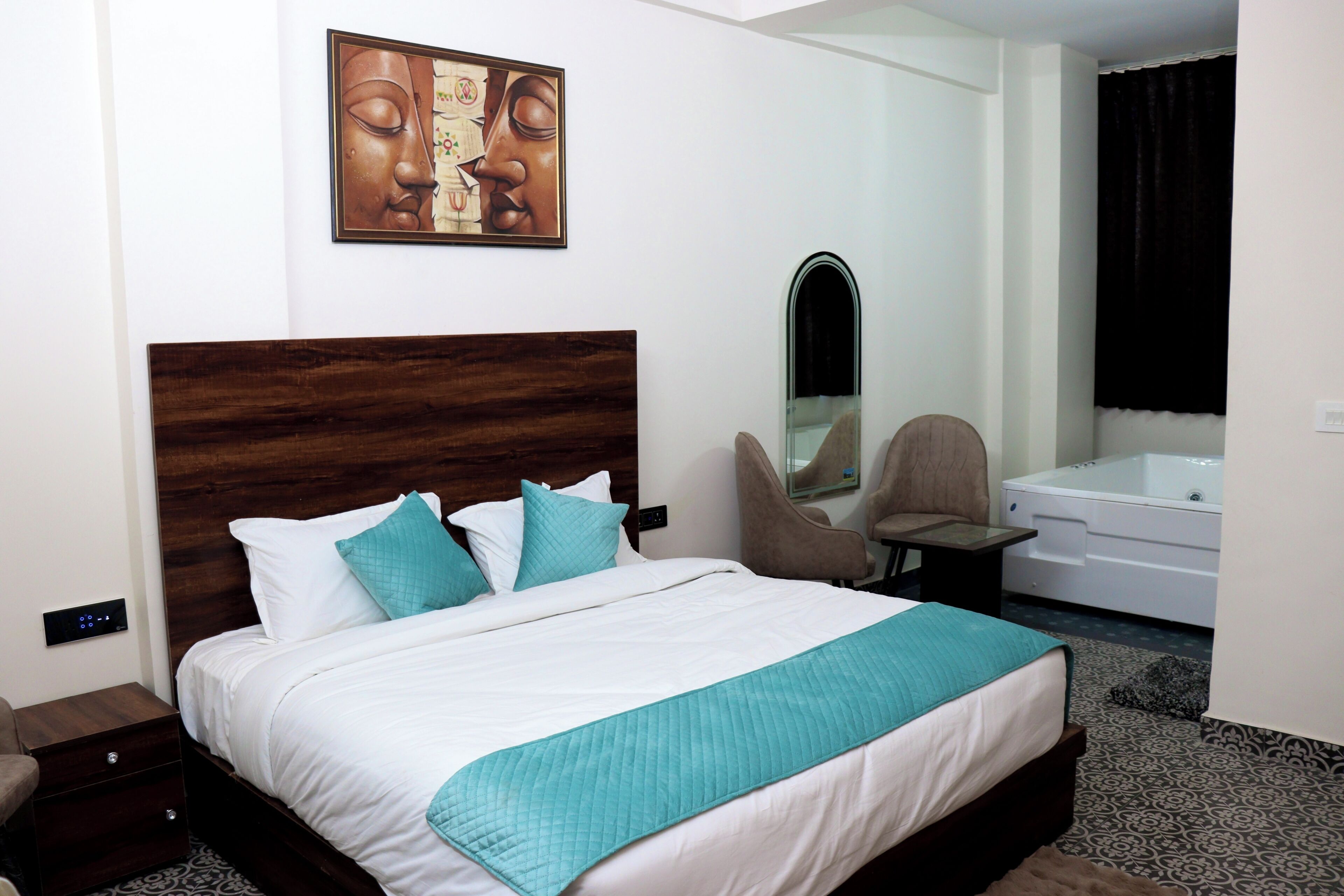 A hotel room with a large bed, a wooden headboard, a mirror, a chair, a bathtub, and a wall-mounted artwork.