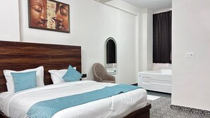 Ein modernes Hotelzimmer mit einem großen Bett, einem Sessel, einem Badezimmer mit Badewanne und einem Wandbild.