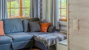 Une pièce chaleureuse avec un canapé d’angle, de grandes fenêtres et un radiateur.