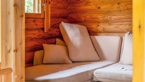 L’intérieur d’un chalet confortable, avec un canapé d’angle et une fenêtre.