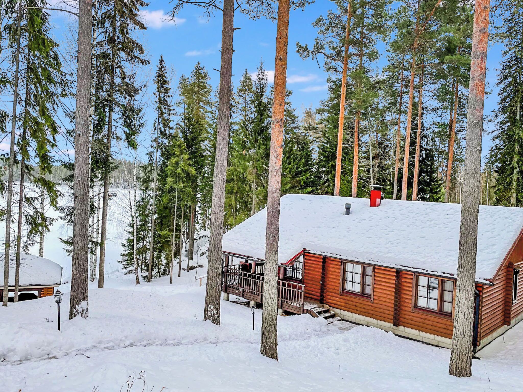 Una cabana amb un teulat cobert de neu, envoltada d'altes pinedes.
