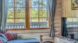 A room with a large window, a sofa, a TV, and a speaker. - Villa norppa by Interhome (Punkaharju)
